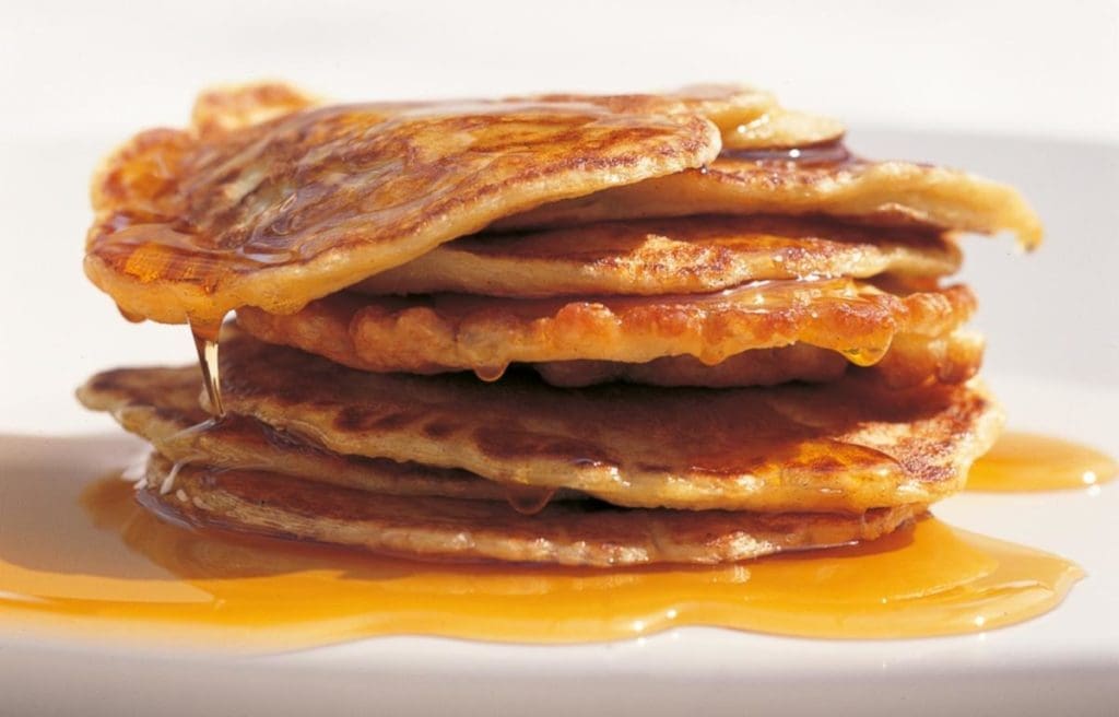 Pouring a thick homemade Maple Syrup Substitute over pancakes Gardenfrontier A pitcher pouring a thick golden brown homemade maple syrup substitute over a stack of pancakes