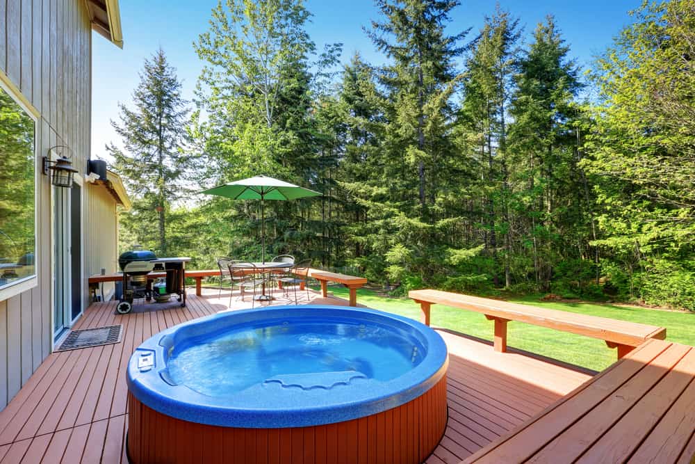 A traditional garden tub setting with a view of nature Gardenfrontier An elegant garden tub placed in a sunroom with a view of a lush green garden