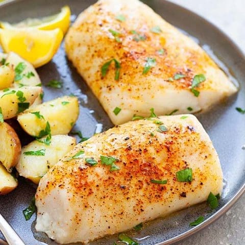 A plate of perfectly Baked Cod Gardenfrontier A perfectly baked cod fillet garnished with fresh parsley and lemon slices