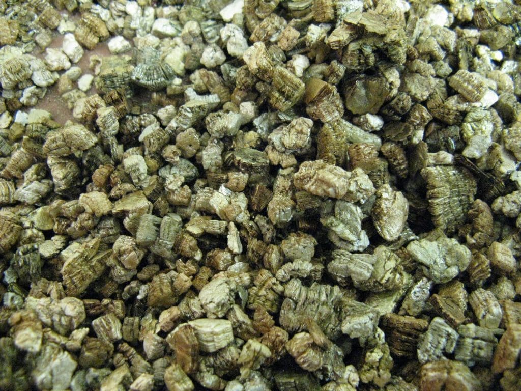 Vermiculite Flakes Gardenfrontier A close up of golden brown flaky vermiculite used for soil amending