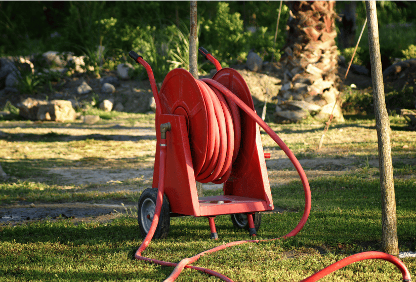 Retractable Garden Hose Reels Gardenfrontier A green retractable garden hose reel mounted on a brick wall